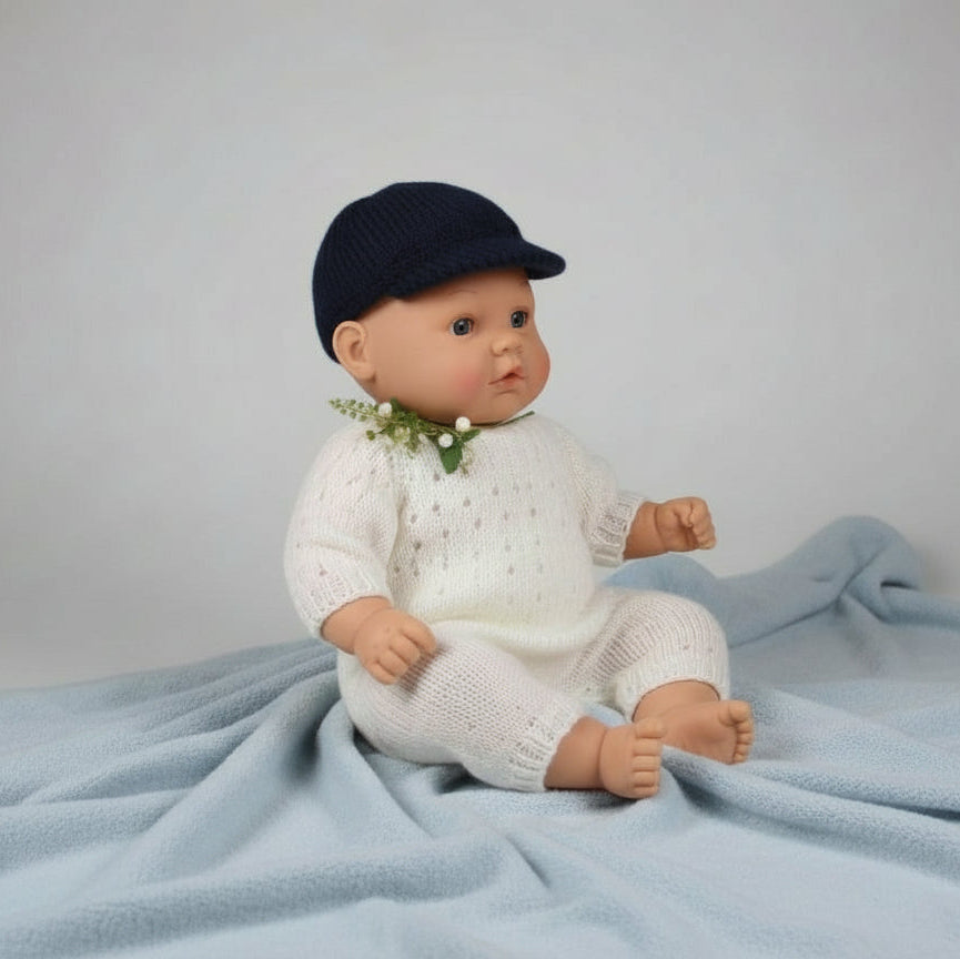 Baby doll wearing a blue cap and white outfit on a gray background