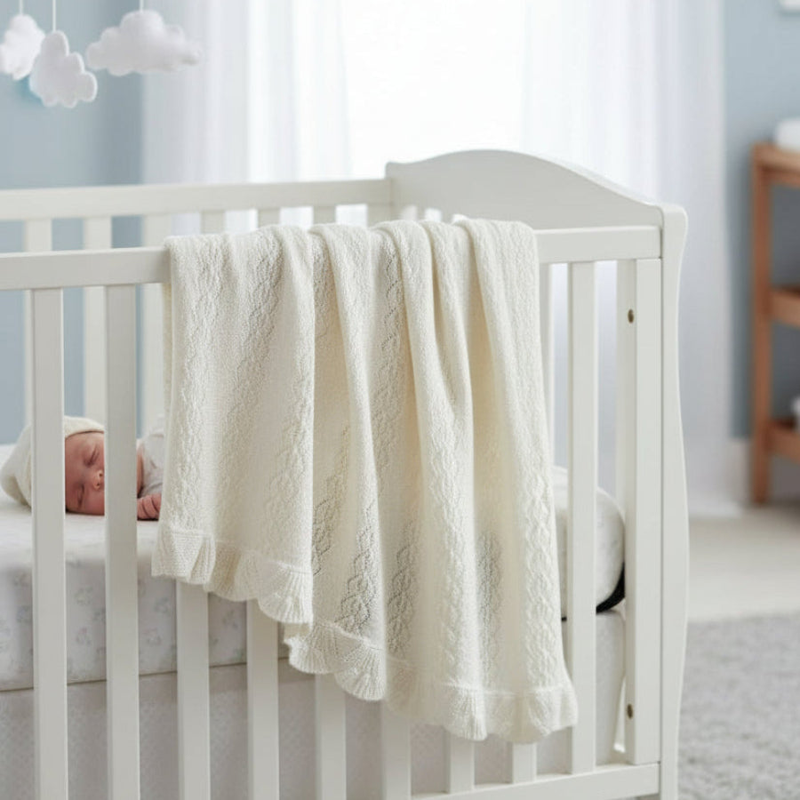 White crib with a textured white blanket in a nursery setting