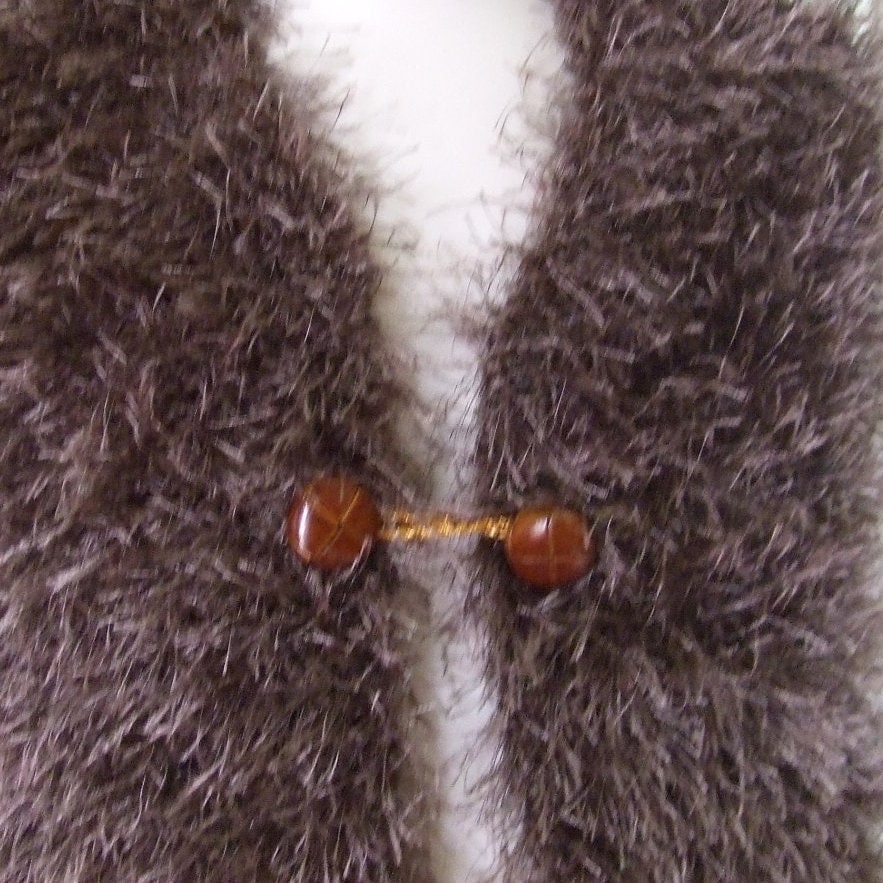 Close-up of a textured brown vest with faux fur fabric with a button and gold thread.