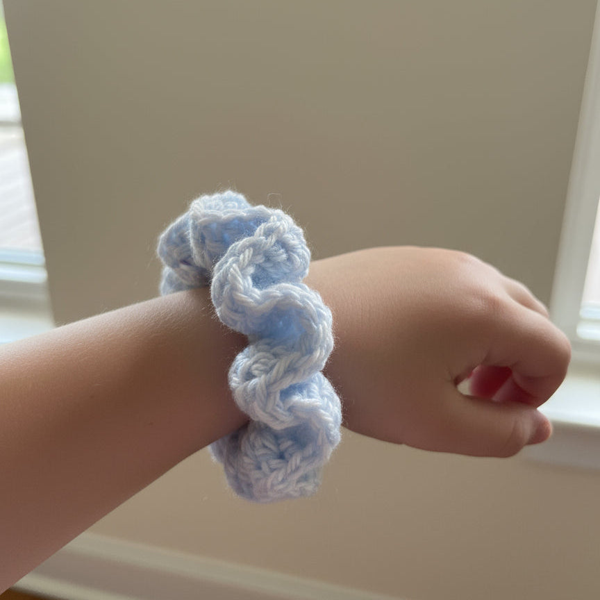 Blue crocheted scrunchie on a little girl's wrist
