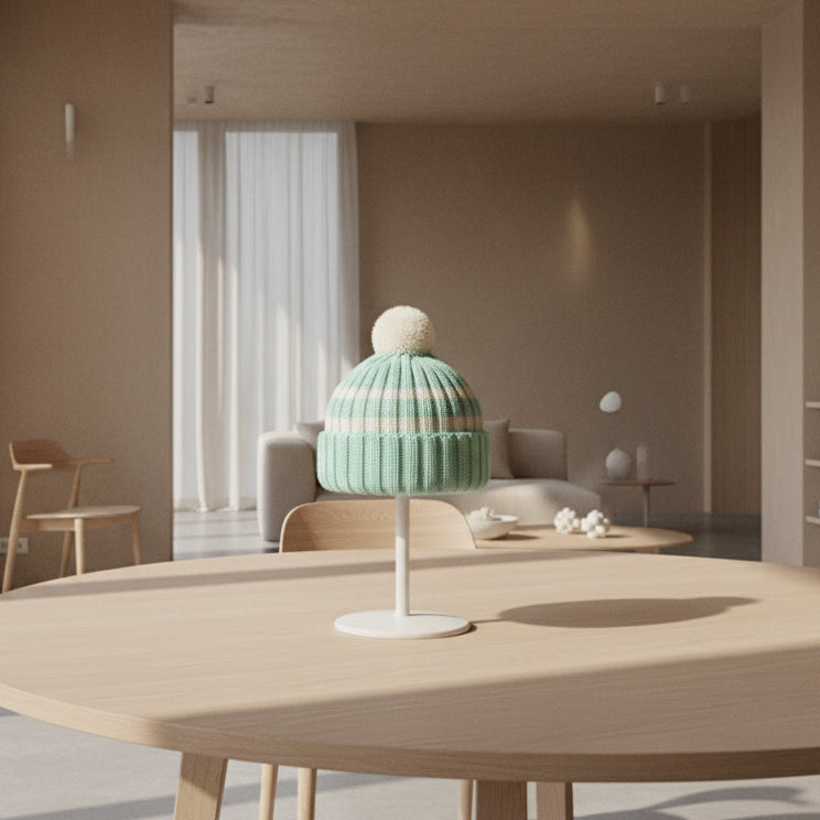 Knitted hat with a striped pattern and pom-pom on a plain background